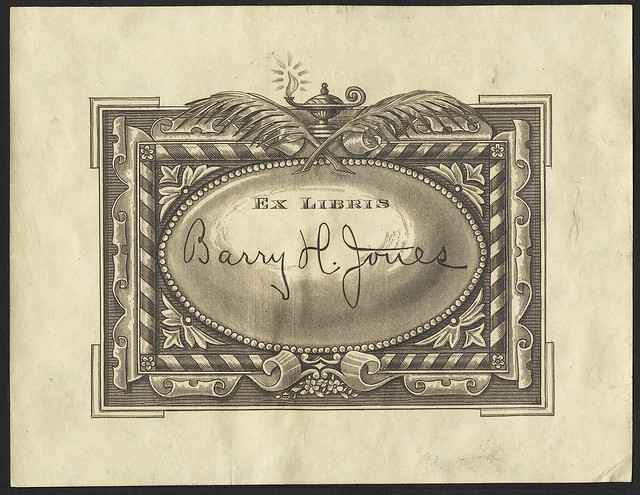 engraved bookplate : ornate striped ribbon border topped by crossed quills