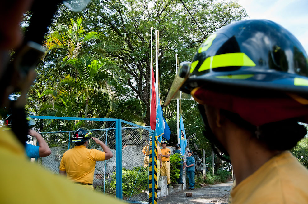 El capitán de la 3ra. Compañía de Sajonia  saluda a la bandera paraguaya y la de la institución durante su izamiento el 12 de mayo antes de comenzar la jornada de prácticas. Así también lo hacen los bomberos voluntarios combatientes poniéndose firmes y con la mirada fija hacia el pabellón patrio. (Elton Núñez)