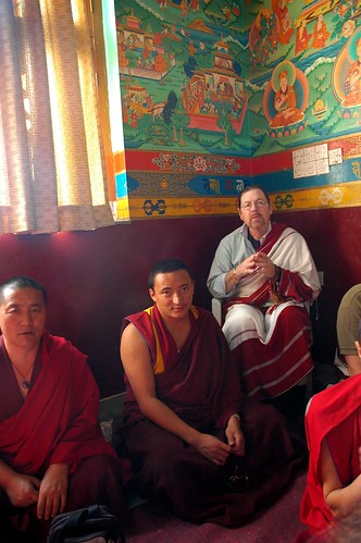 Western practitioner Tashi Paljor wearing an adi, monk friends wearing traditional robes and shawls, in the corner of Tharlam Monastery, wall murals, Sakya Lamdre, Boudha, Kathmandu, Nepal by Wonderlane