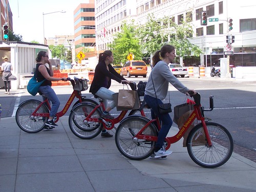 3 people riding Capital Bikeshare bikes on M Street NW, after shopping