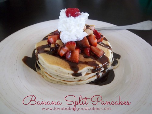 Banana Split Pancakes stacked on plate with whipped cream, strawberries and chocolate syrup.