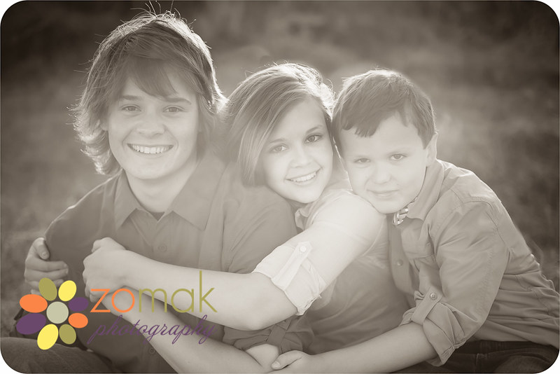 black and white photo of Three siblings embracing in the setting sun at spring meadow park in helena montana