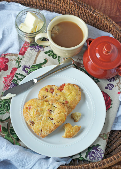 Two heart-shaped scones filled with strawberries on a white plate