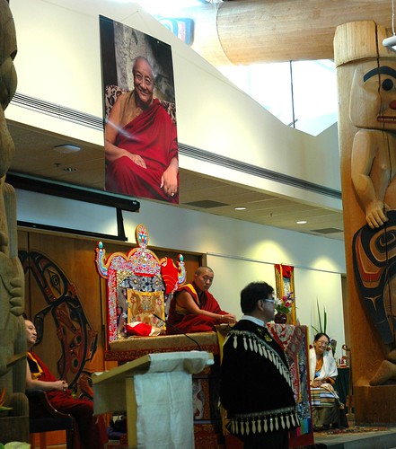 Canadian First Nations representative in traditional jacket welcomes Dilgo Khyentse Yangsi Rinpoche (on the throne) to the long house, reception for Khyentse Yangsi Rinpoche, photo of Dilgo Khyentse Rinpoche, totems, Lotus Speech, Vancouver BC, Canada by Wonderlane