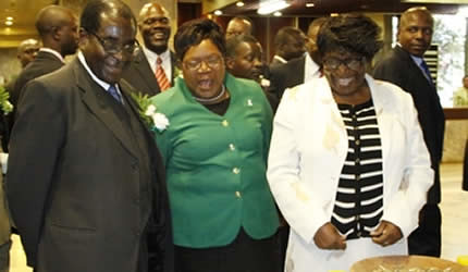 President Mugabe and Vice President Joice Mujuru share a lighter moment with Mrs Thecla Madziwa as she explains nutritional values in traditional foods at the launch of the National Food Policy in Harare on May 16, 2013. by Pan-African News Wire File Photos