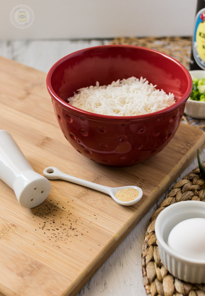white rice in a red bowl with garlic powder, white egg and black pepper on a wooden chopping board 