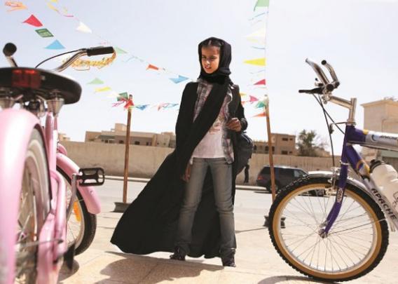 Wadjda, a young girl wearing a niqab, stares at a bike