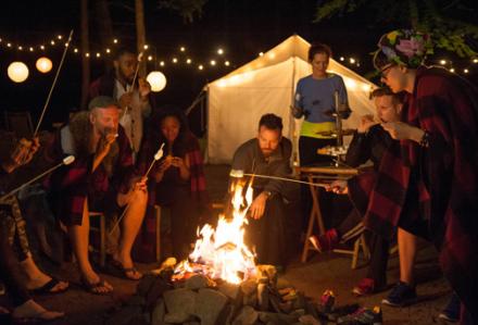The project runway crew roasting marshmallows in a fancy campsite