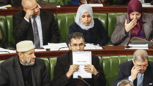 A Tunisian parliament member holds up a copy of a document that reads in Arabic and the "draft constitution for Tunisia. The country is attempting develop a governing document three after the removal of Ben Ali. by Pan-African News Wire File Photos