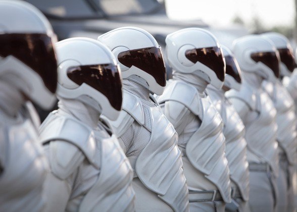 Peacekeepers in Catching Fire wear face shieids and stand in a long line