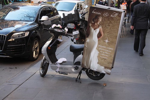 Wedding gown advertising tied to a parked electric bike on Collins Street