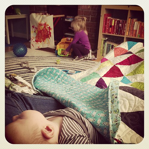 Scenes from a mama quilter's life: binding with one on the lap and the other playing!