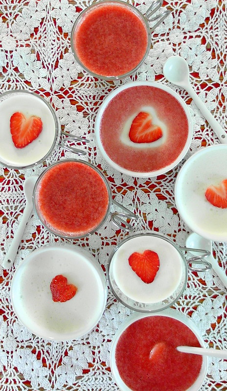 Overhead shot of ramekins of Caramelized Honey and Lavender Panna Cotta with strawberry cut in heart shapes garnish.