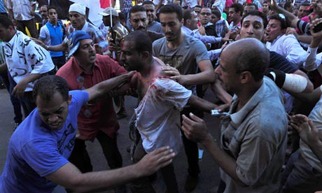 Egyptians help a wounded man after clashes in Alexandria. Political tensions escalated in late June 2013. by Pan-African News Wire File Photos