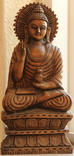 Haloed Buddha statue in wood, holding his right hand in the perfection mudra, and a vase in the left, feet and legs in the lotus position, South Bay Vajrayana, Cupertino, Silicon Valley, California, USA by Wonderlane
