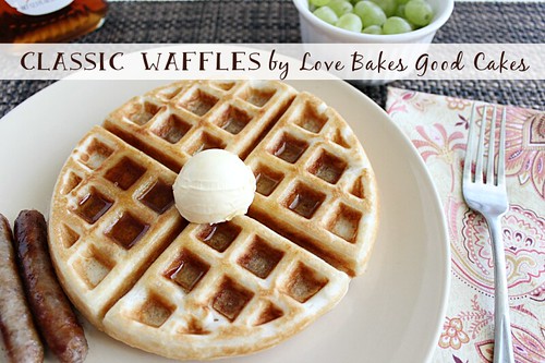 Classic Waffles on a plate with butter, sausage links and green grapes.