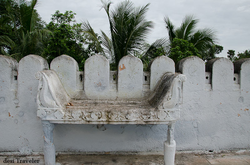 A stone bench on the temple roof with coconut trees in background