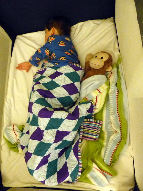Eskil and Monkey George asleep in the hotel's travel cot