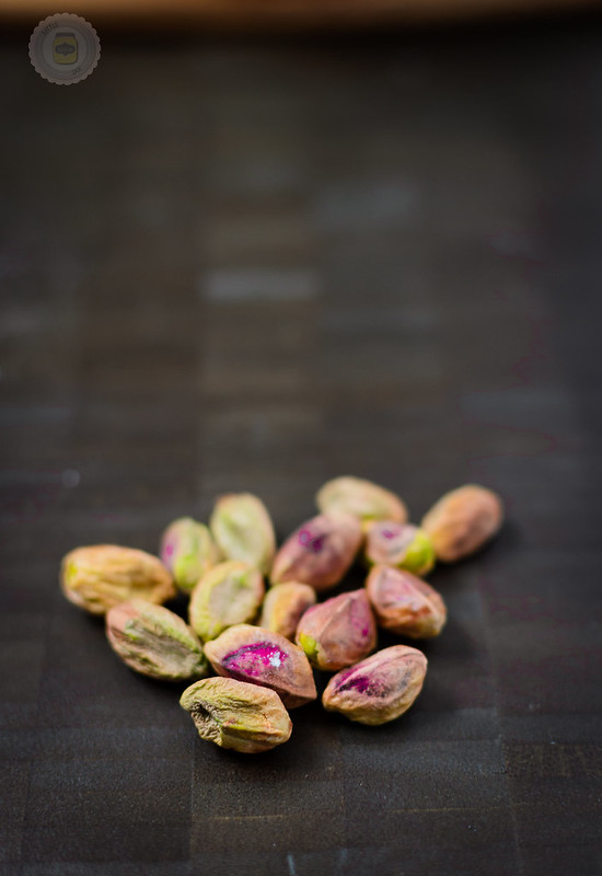 Pistachios pictured on a dark surface