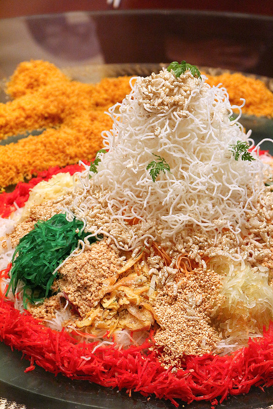 The towering yusheng is sprinkled with gold dusted rice crispies