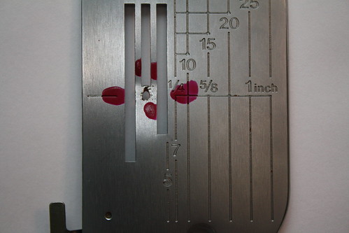 This is not what a needle plate should look like - the repairman marked it up with the nail polish to draw attention to the needle hole, where the damage is