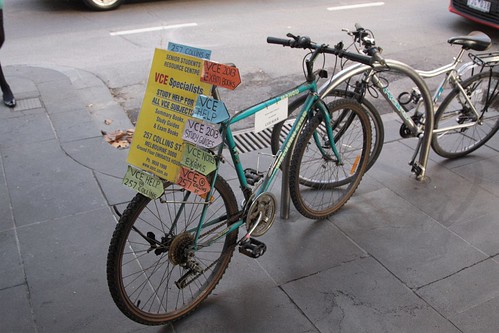 'VCE study centre' advertising tied to a parked bike on Collins Street