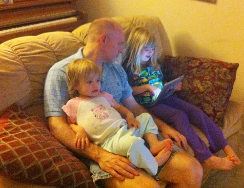 Lucy watches Bubble Guppies on The Guy's lap while Catie shows him her iPad game. #love