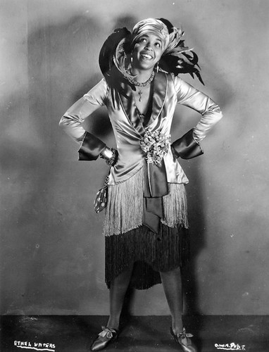 Ethel Waters, a black singer, wearing a fancy dress with giant feathers in the back