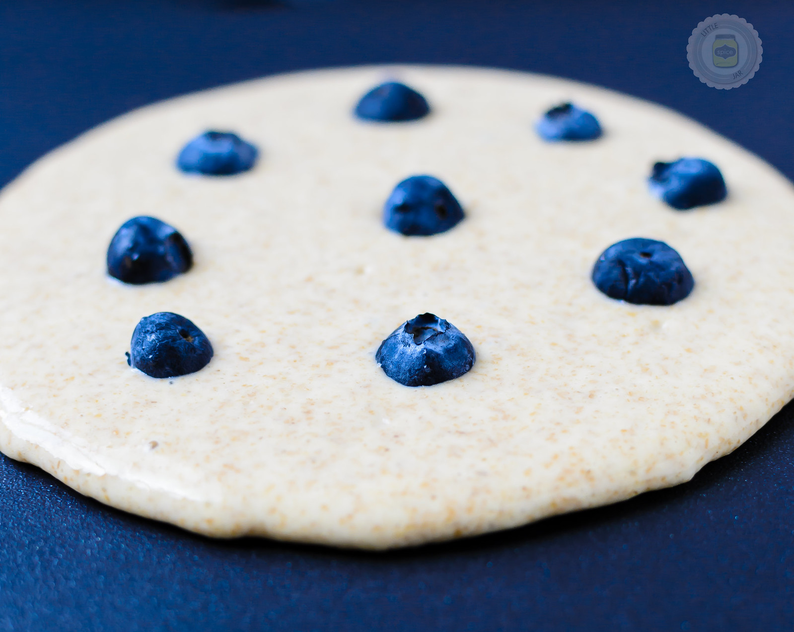 cooking pancake on griddle with blueberries before flipping