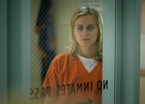 Piper, a blonde white woman, behind a prison door