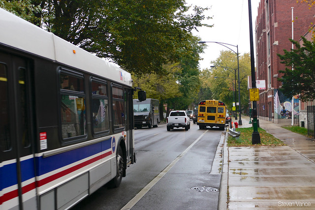 CTA bus has to wait because illegally parked vehicles on both sides make it too narrow to pass