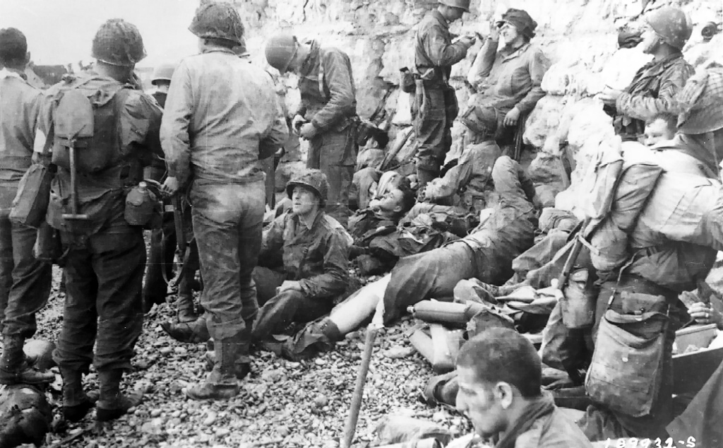 American assault troops of the 3d Battalion, 16th Infantry Regiment, 1st U.S. Infantry Division, takes a breather before moving onto the continent at Colleville-Sur-Mer