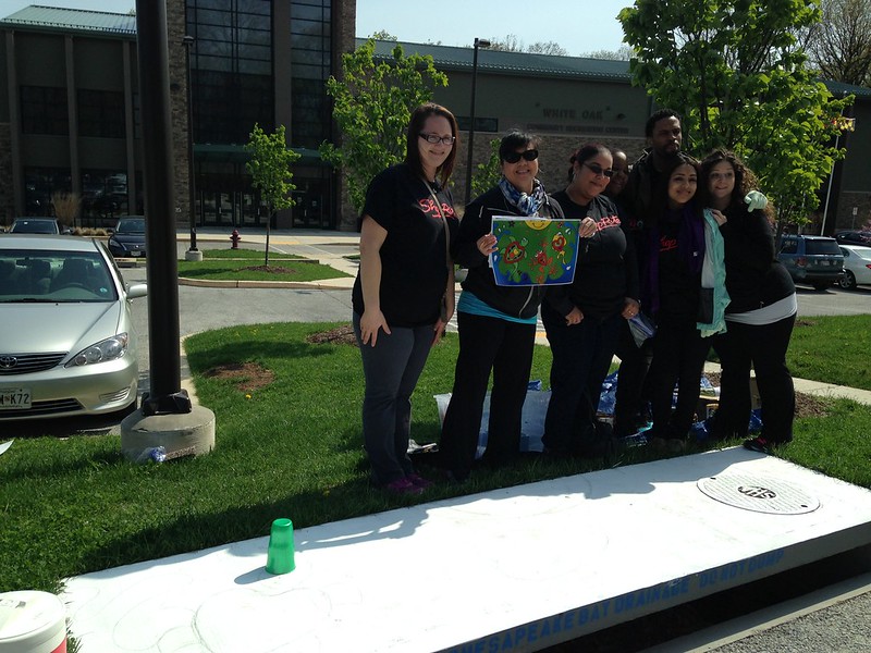 Volunteers standing next to a white storm drain with a picture of the art.