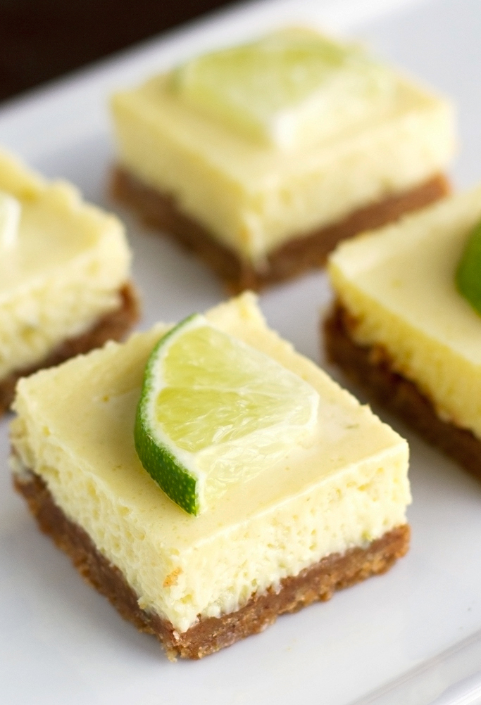 cut up key lime pie squares on white plate topped with lime wedge