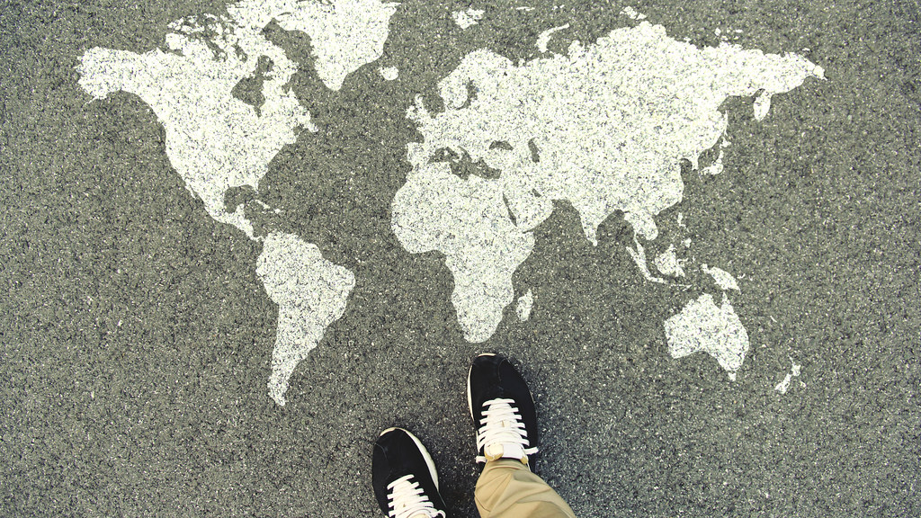 A map of the world painted on the ground with a view of a persons shoes