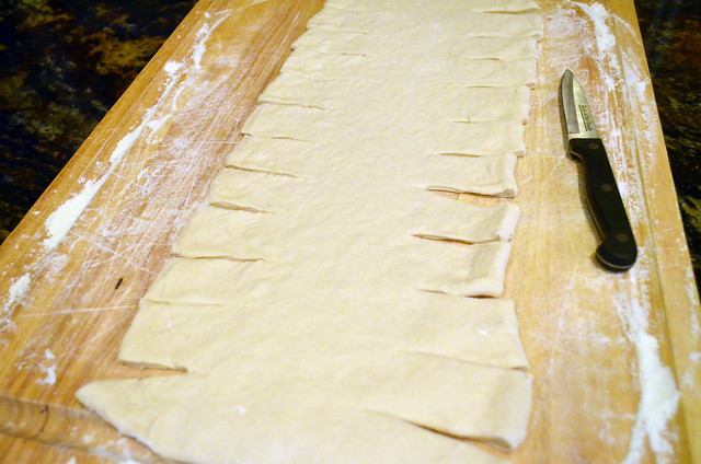 Rolled out dough with small cuts made on the long sides of the dough rectangle.