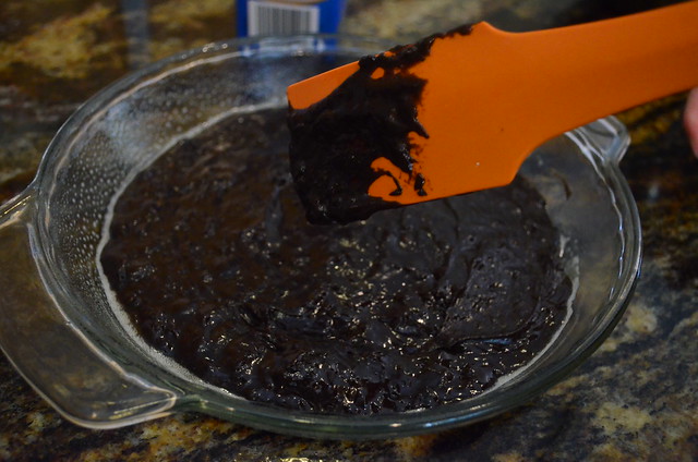 The mixture being transferred to a greased glass pie pan with a spatula.