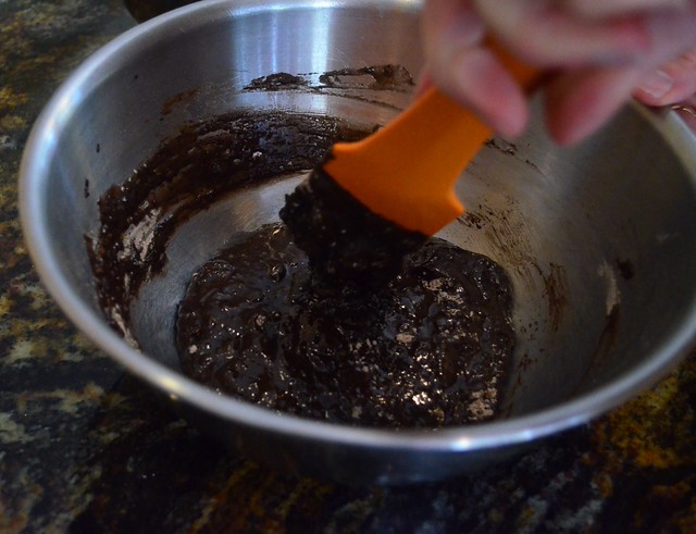 A silicone spatula mixing together the wet and dry ingredients in a bowl.