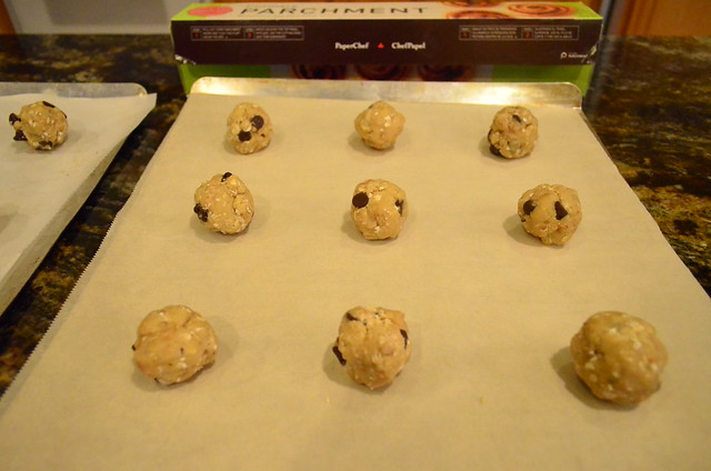 Raw cookie dough rolled into balls on to a parchment paper lined cookie sheet.