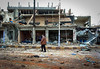Syrian man pass next to a damaged house after a suicide bomber blew up a vehicle in the Syrian city of Daraa