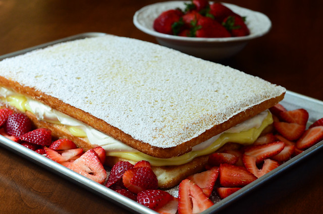 The finished Strawberries and Cream Cake, with sliced strawberries arranged around the cake. 