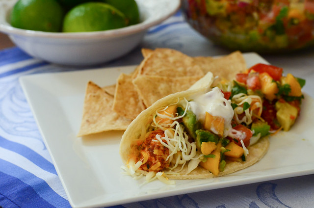 A chicken taco with mango avocado salsa served on a plate with tortilla chips.