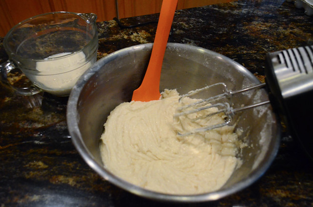 The mixture being beaten with a hand mixer and silicone spatula.