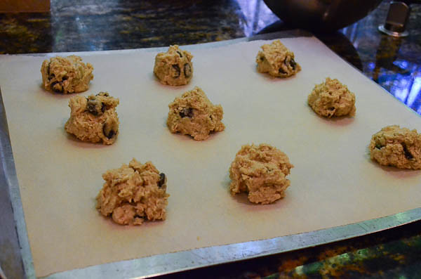 Several balls of cookie dough are arranged on a parchment line cookie sheet.