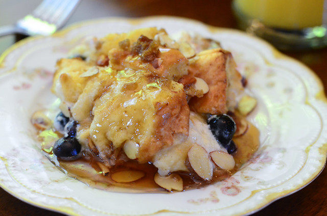 A close up image of Blueberry Almond French Toast Bake on a china plate with maple syrup.