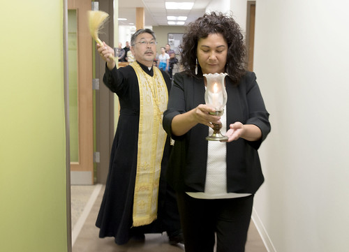 a20160618-071-TyExecutive Director Jaylene Peterson-Nyren carries a candle as she leads Father Thomas Andrew through the building during a Russian Orthodox blessing. otkas-Elders-Center