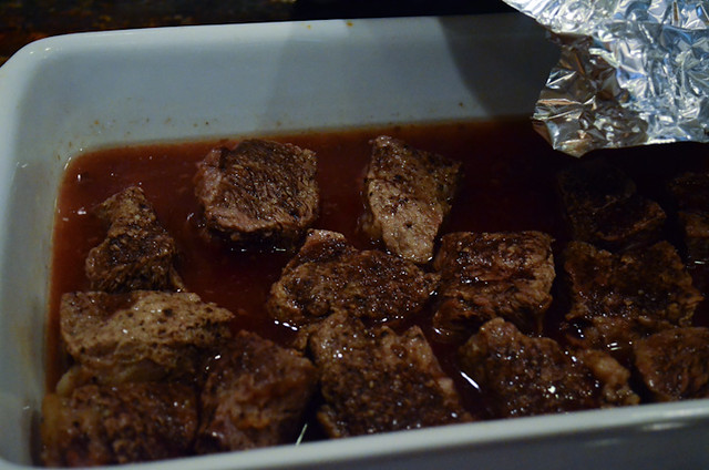 Foil is removed from the casserole dish to reveal the cooked beef.