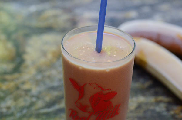 A close up of a glass of the smoothie with frozen bananas in the background.