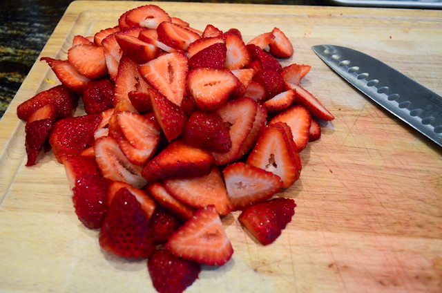 Strawberries that have been cut into slices on a cutting board.