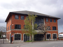 The same three-storey detached building shown in the first image in this article.  The trees are less leafy here, and a central glassed-in portion of the building is visible.